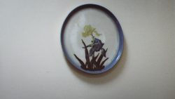 Image of a hanging ceramic plate with blue border and a yellow iris and blue iris.