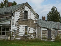 Image of old wooden house with peeling white paint.