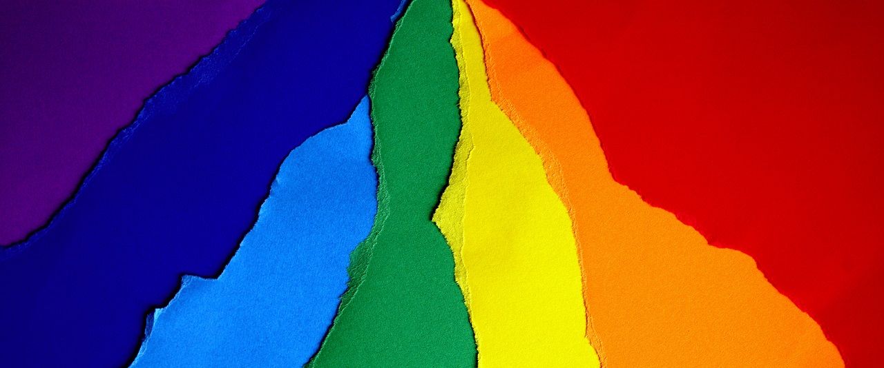 A queer rainbow made of ripped construction paper