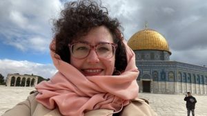 Lia Tarachansky smiling in the foreground of an outdoor photo with the Judaic Temple Mount in the background.