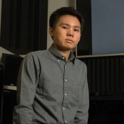 A portrait photo of Graduate Research Associate Haoran Chang wearing a gray button down shirt in a cinema.